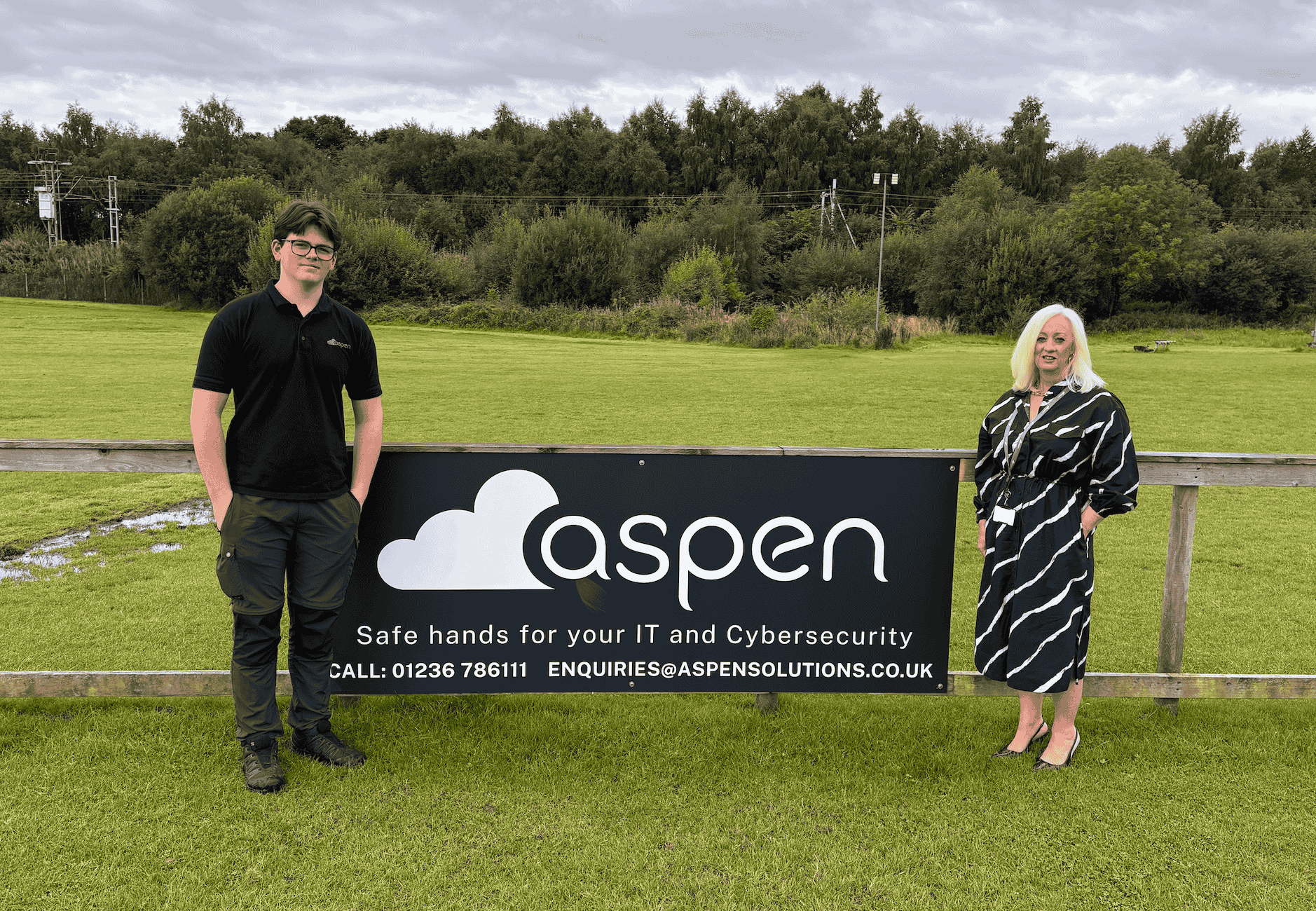 aspen solutions team at rugby stadium with signage